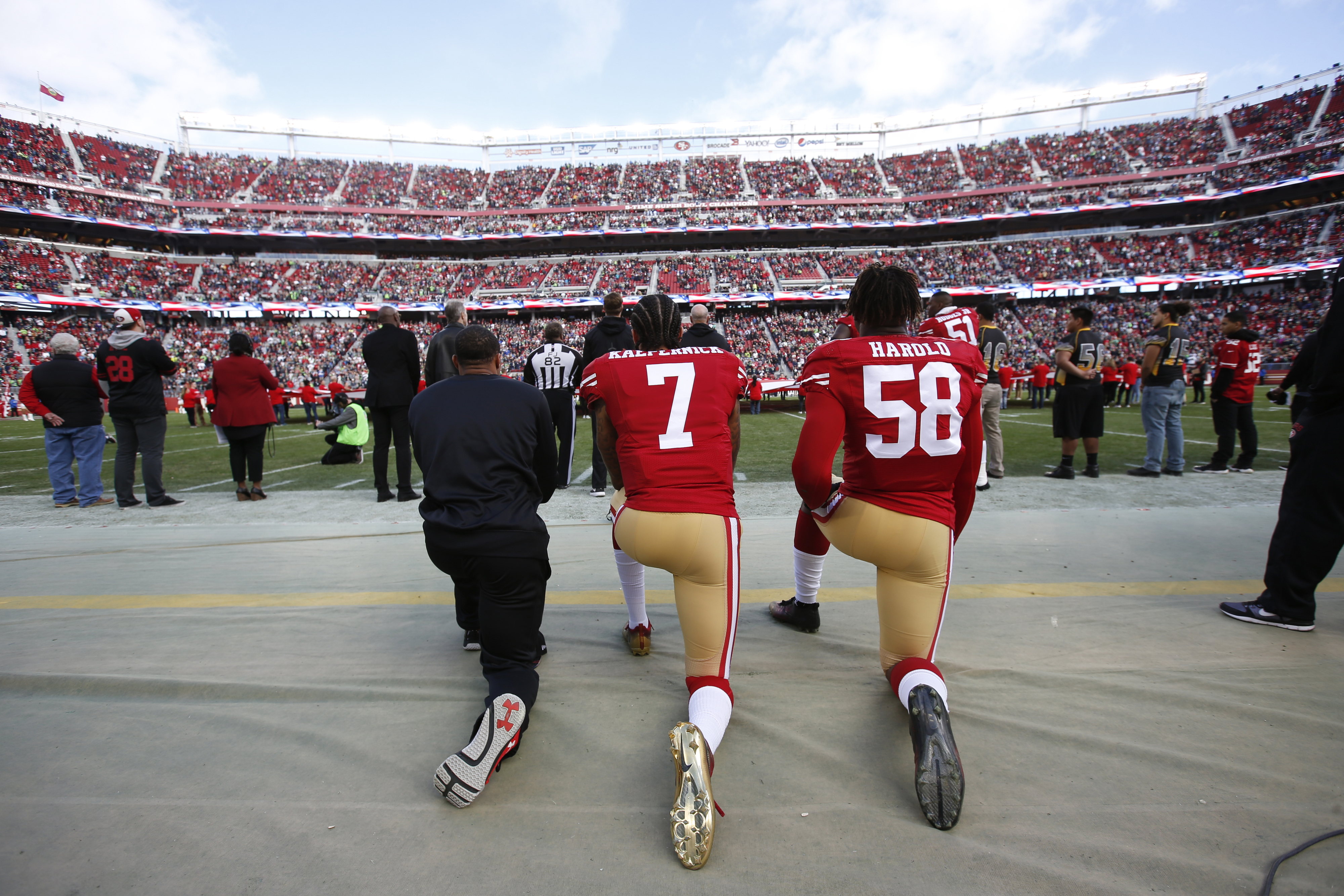 Colin Kaepernick #7 and Eli Harold #58 of the San Francisco 49ers kneel on the sideline, during the anthem