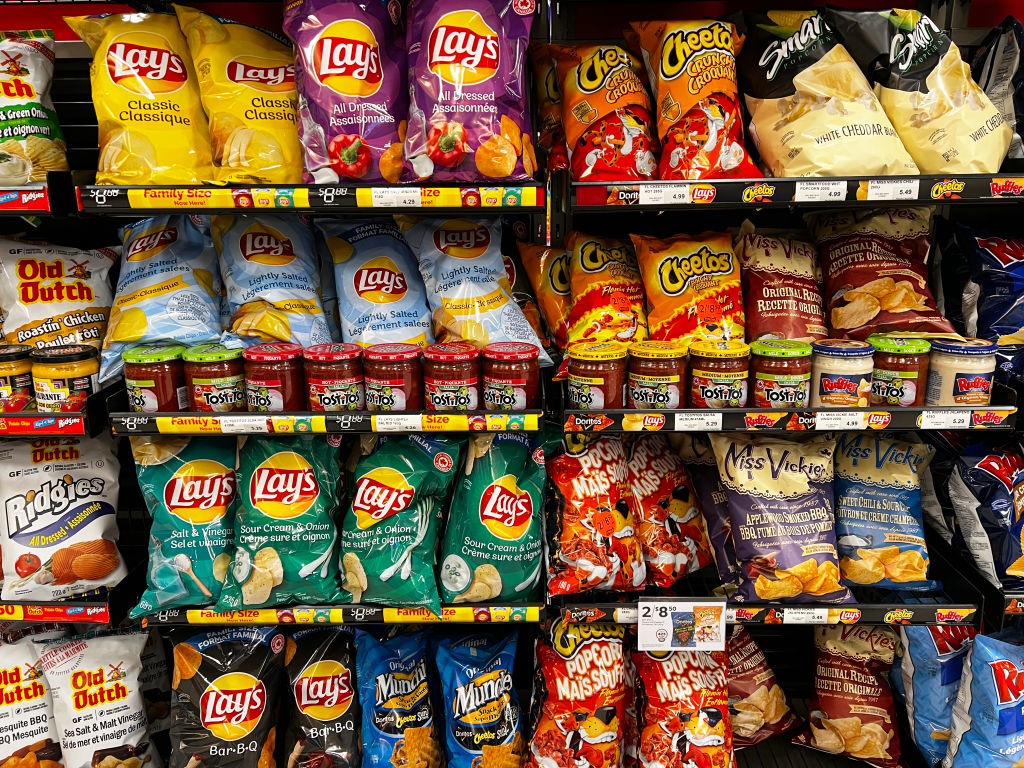 An aisle of chips, cheese puffs, popcorn, and other snacks at the market