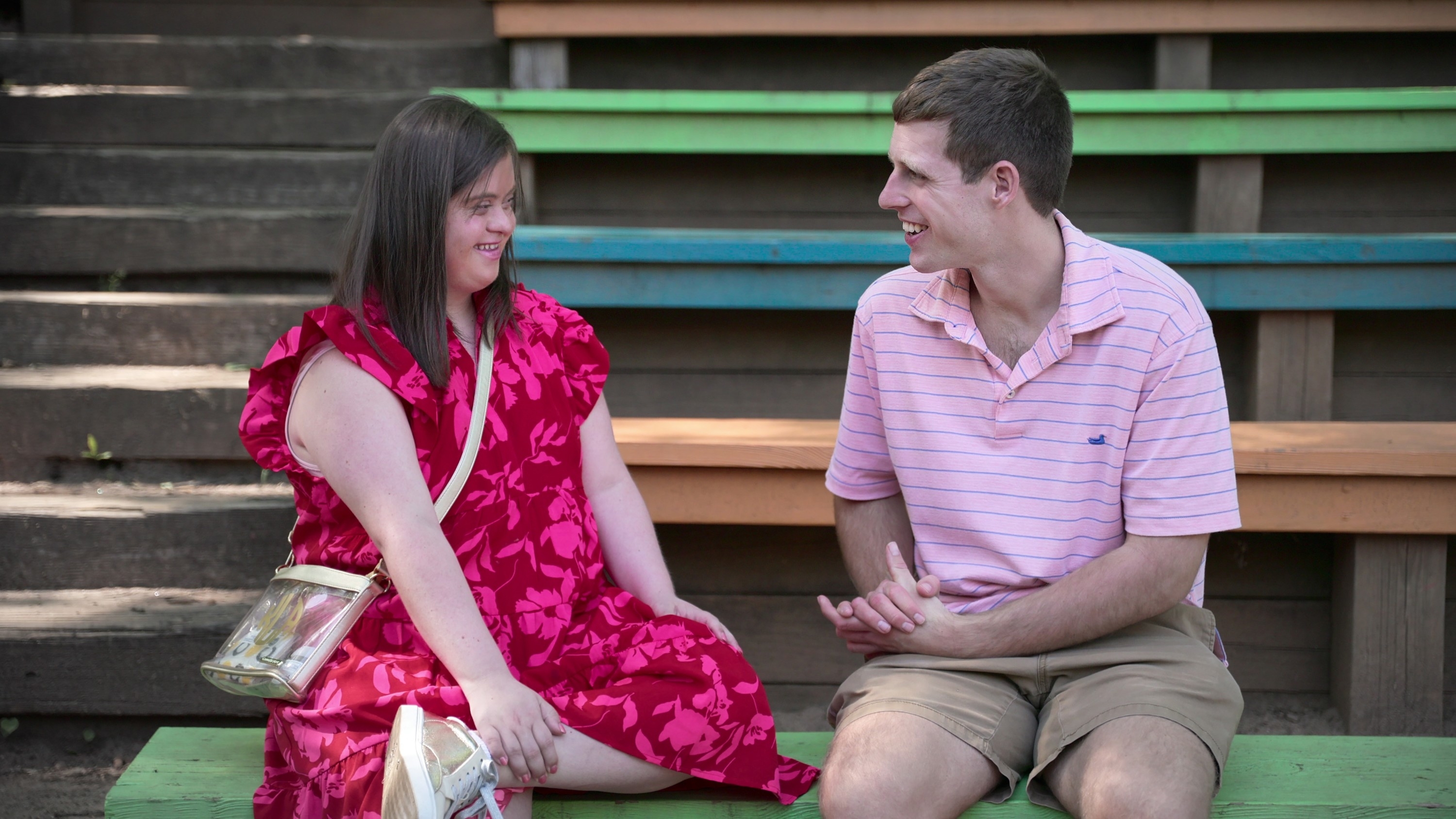 man and woman sitting on park bench smiling at each other