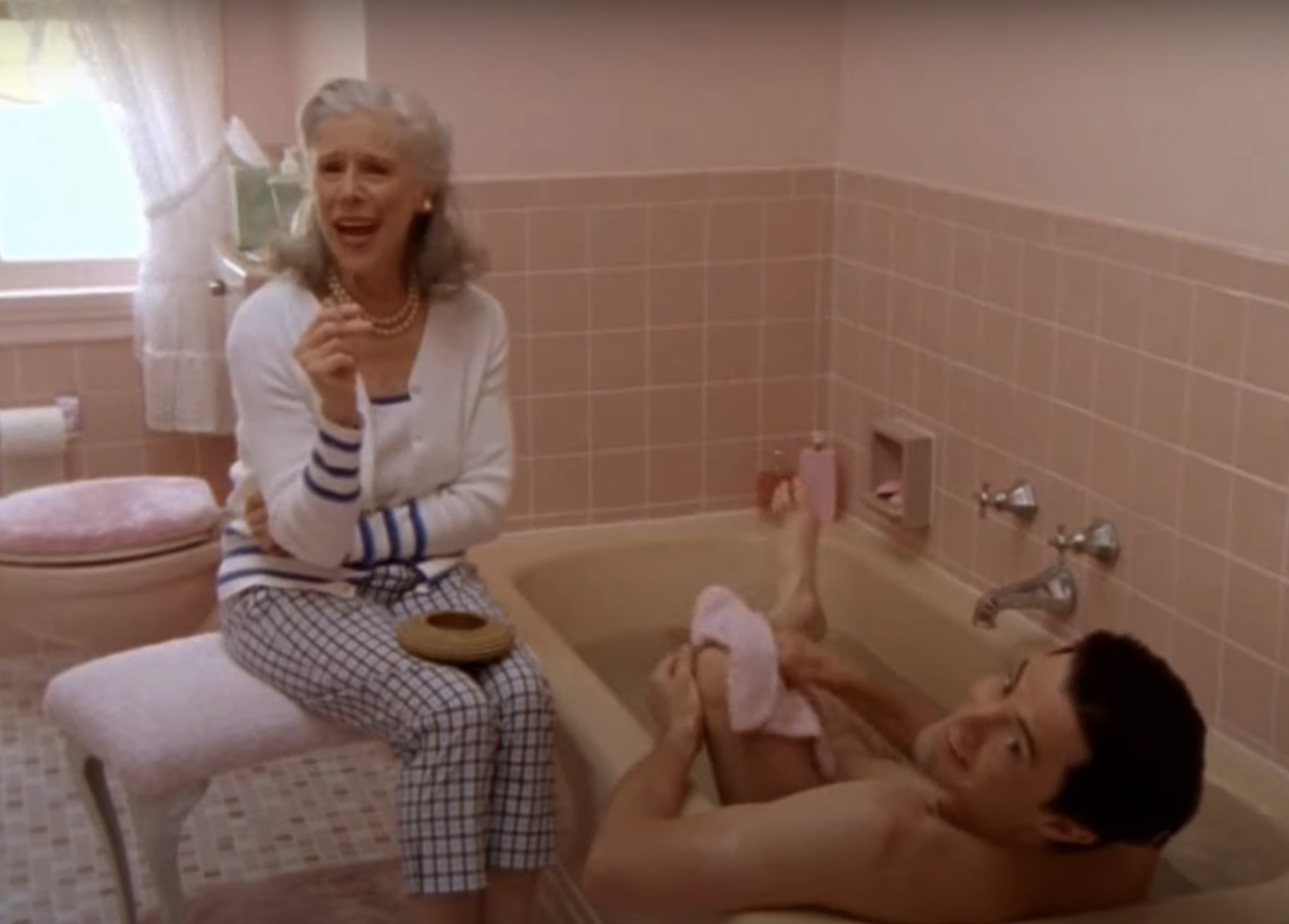woman smoking in the bathroom while a man takes a bath