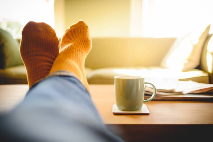 Man wearing orange socks has his legs crossed, feet up on the coffee table
