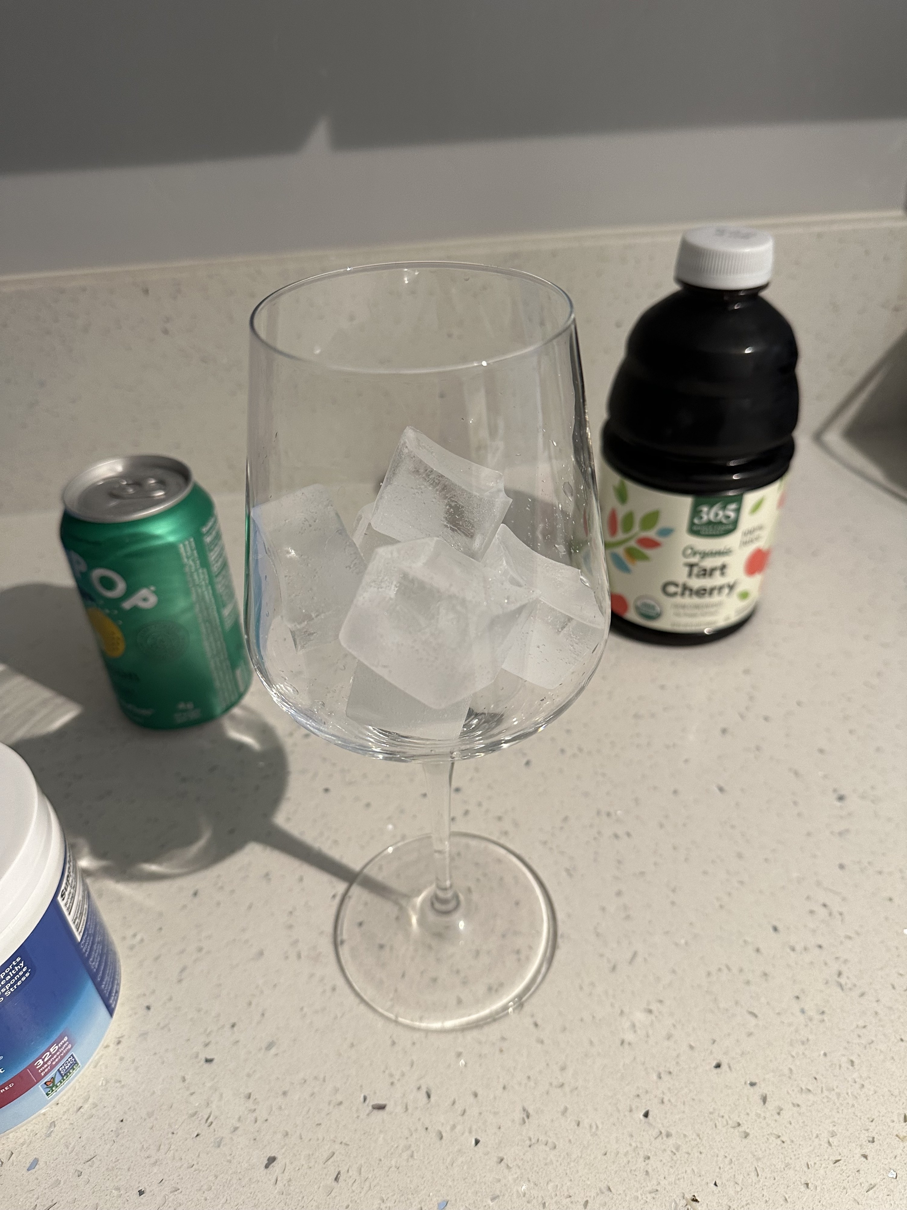 A wine glass with ice next to a bottle of tart cherry juice