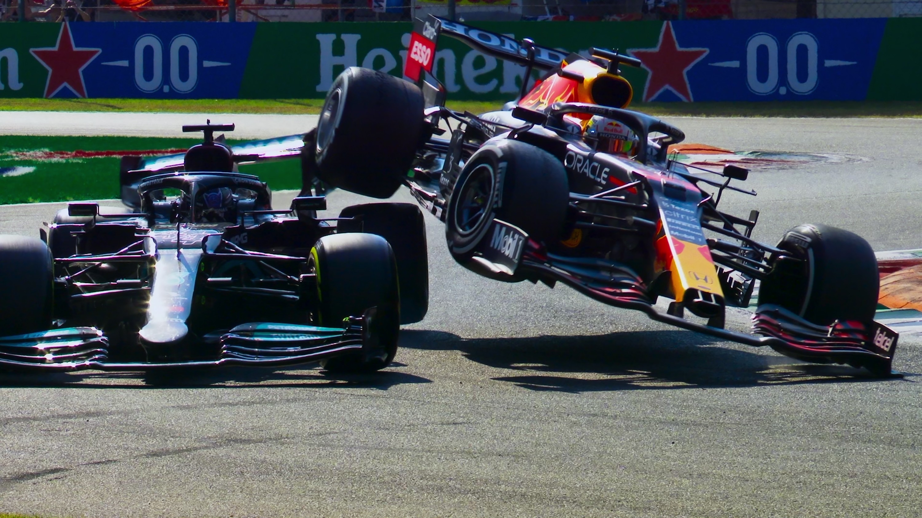 one formula one car with its right side hovering above a second car as it turns sharply on the course