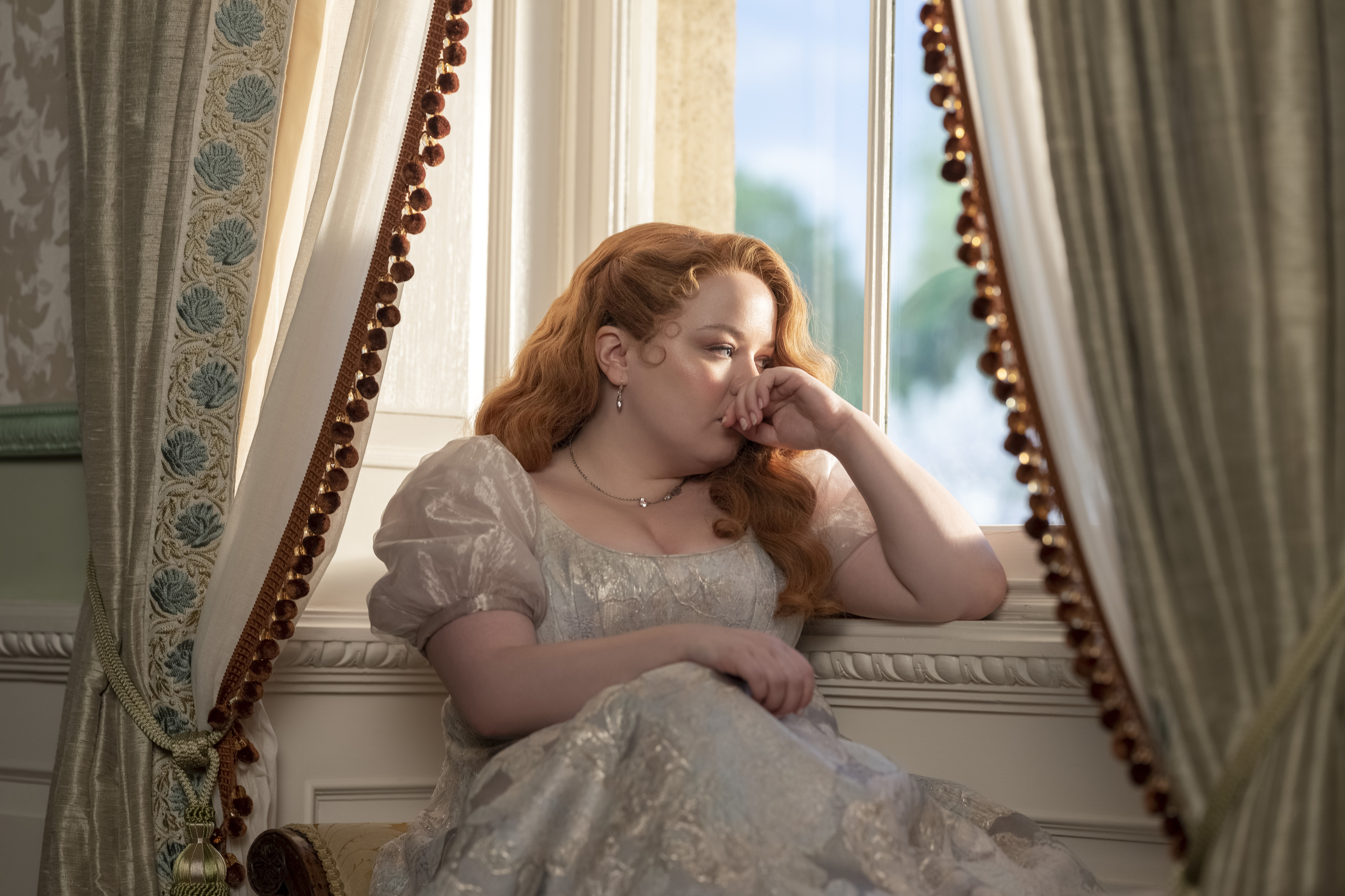 woman in regency wear looking pensive by the window