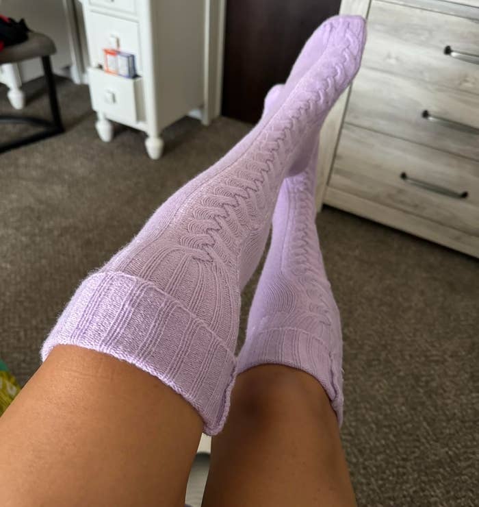 a reviewer photo of legs wearing the lavender cable-knit socks