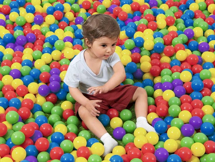 kid sitting in a multicolor ball pit