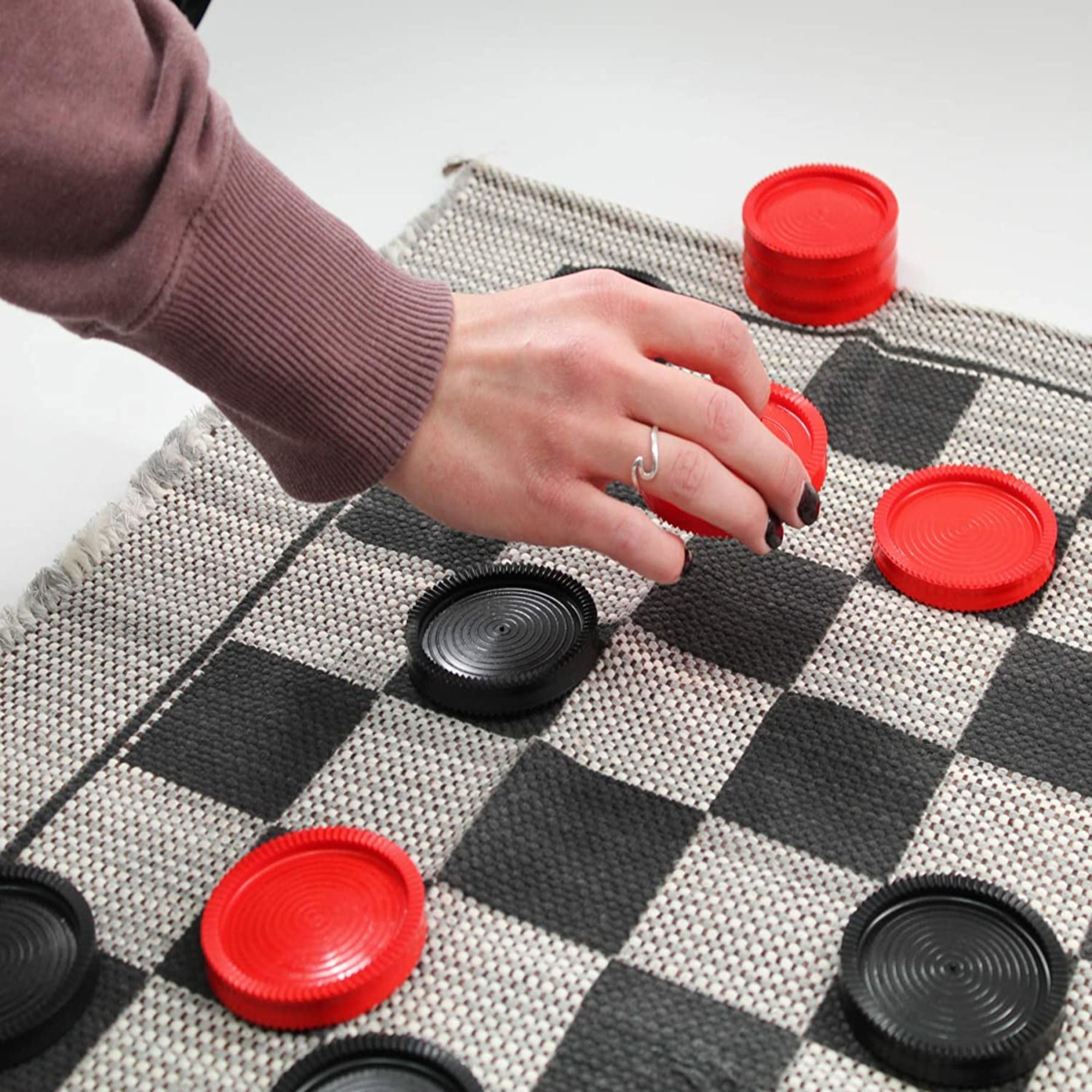 a hand moving checkers on the checkerboard