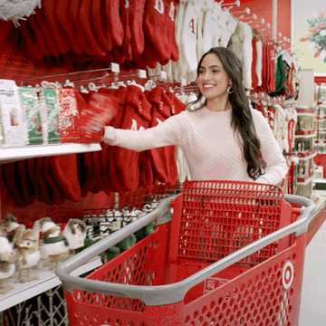 A woman pushing a target cart and putting everything in the aisle into it.