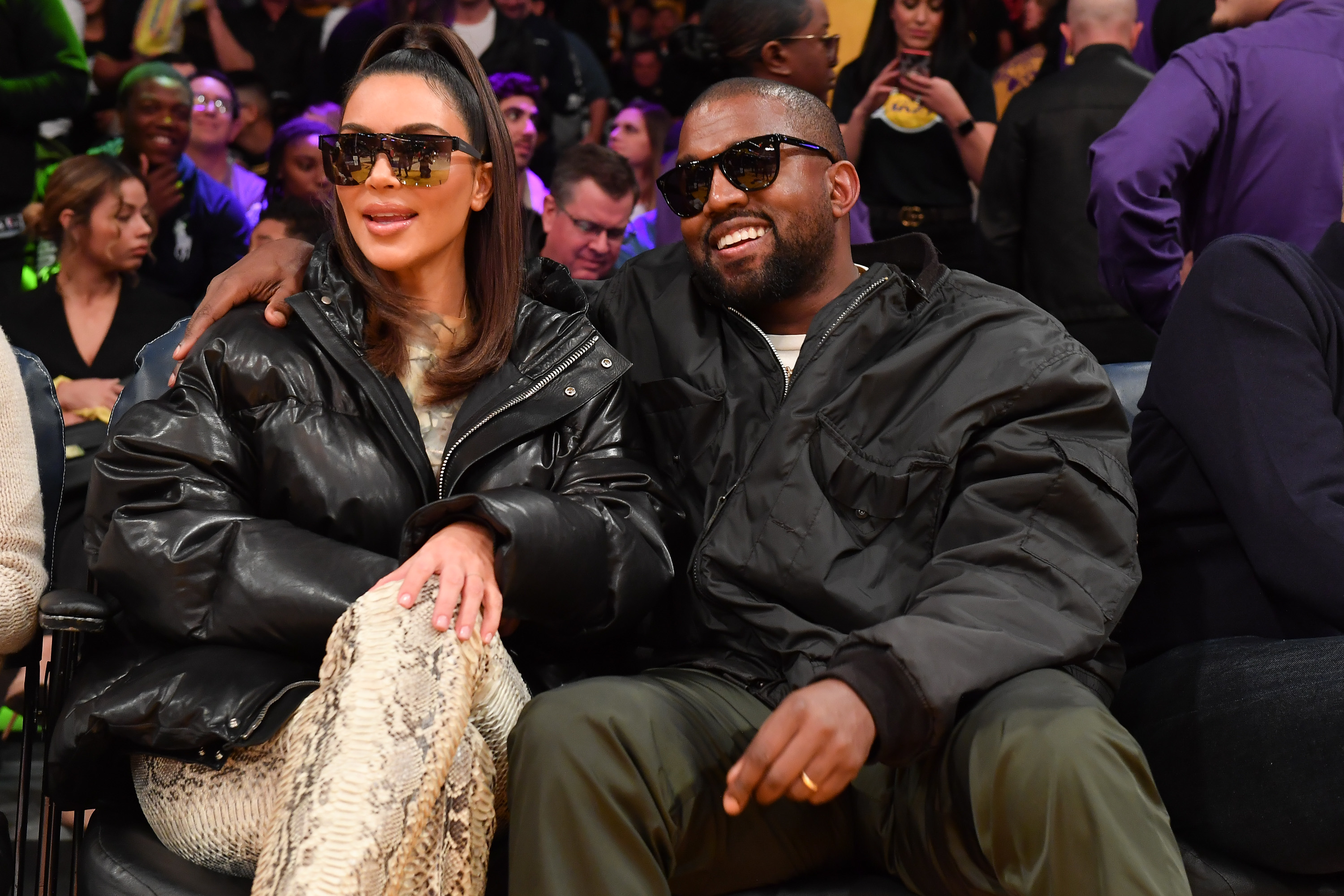 Kim and Ye sitting together and smiling at a sports event
