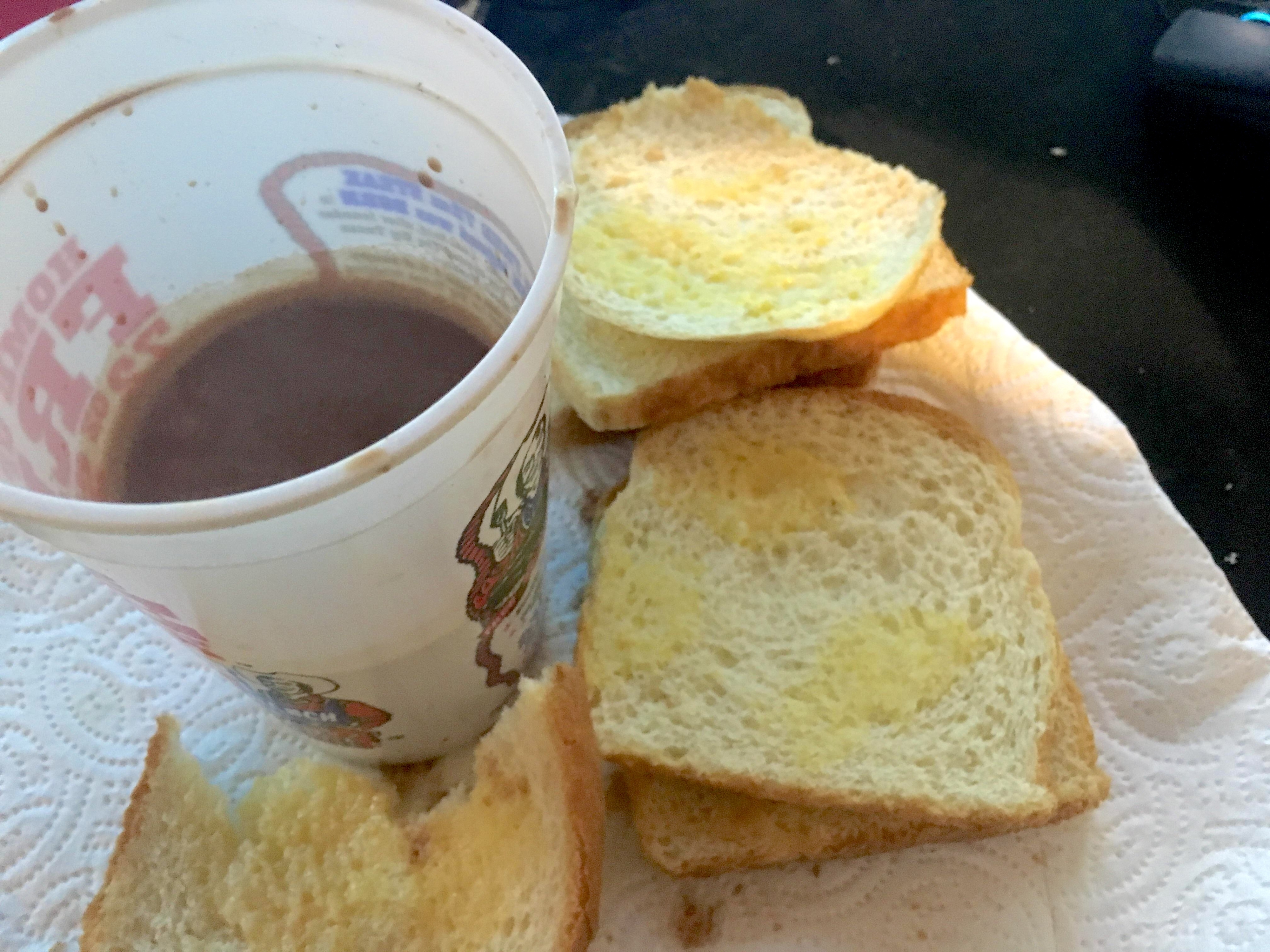 Buttered toast surrounding a plastic cup of hot chocolate