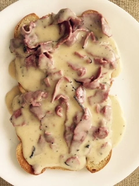 Two pieces of toast smothered in gravy and sliced beef