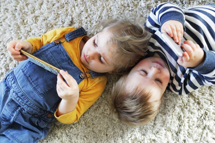 Two babies laying on the carpet to gether