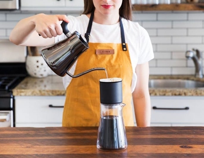 model pouring hot water into cup with the black electric pour over kettle