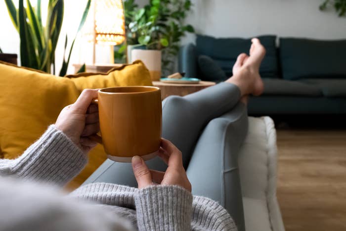 a person lounging on the couch holding a mug