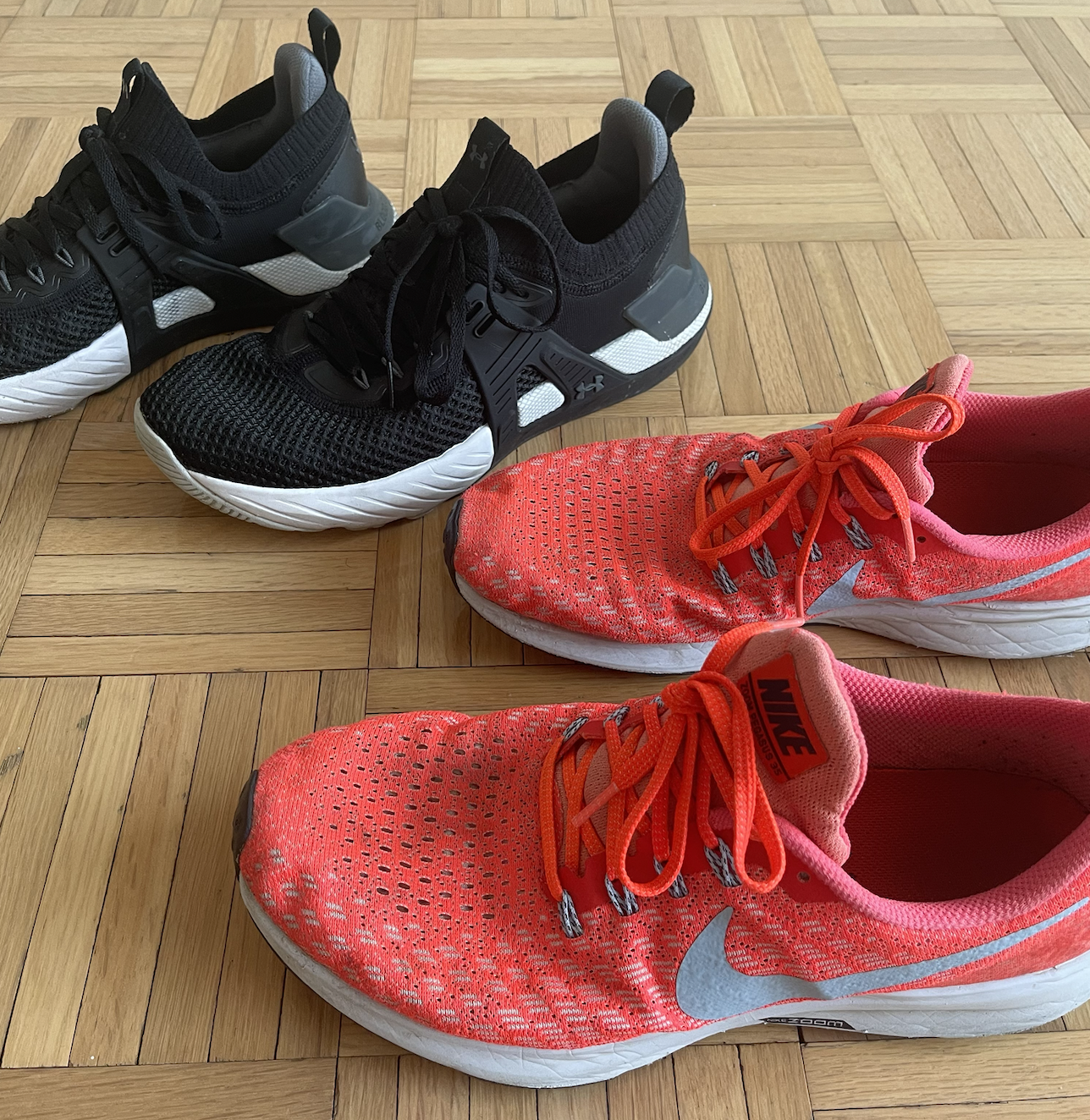A close-up of two pairs of my running shoes, one black and the other orange