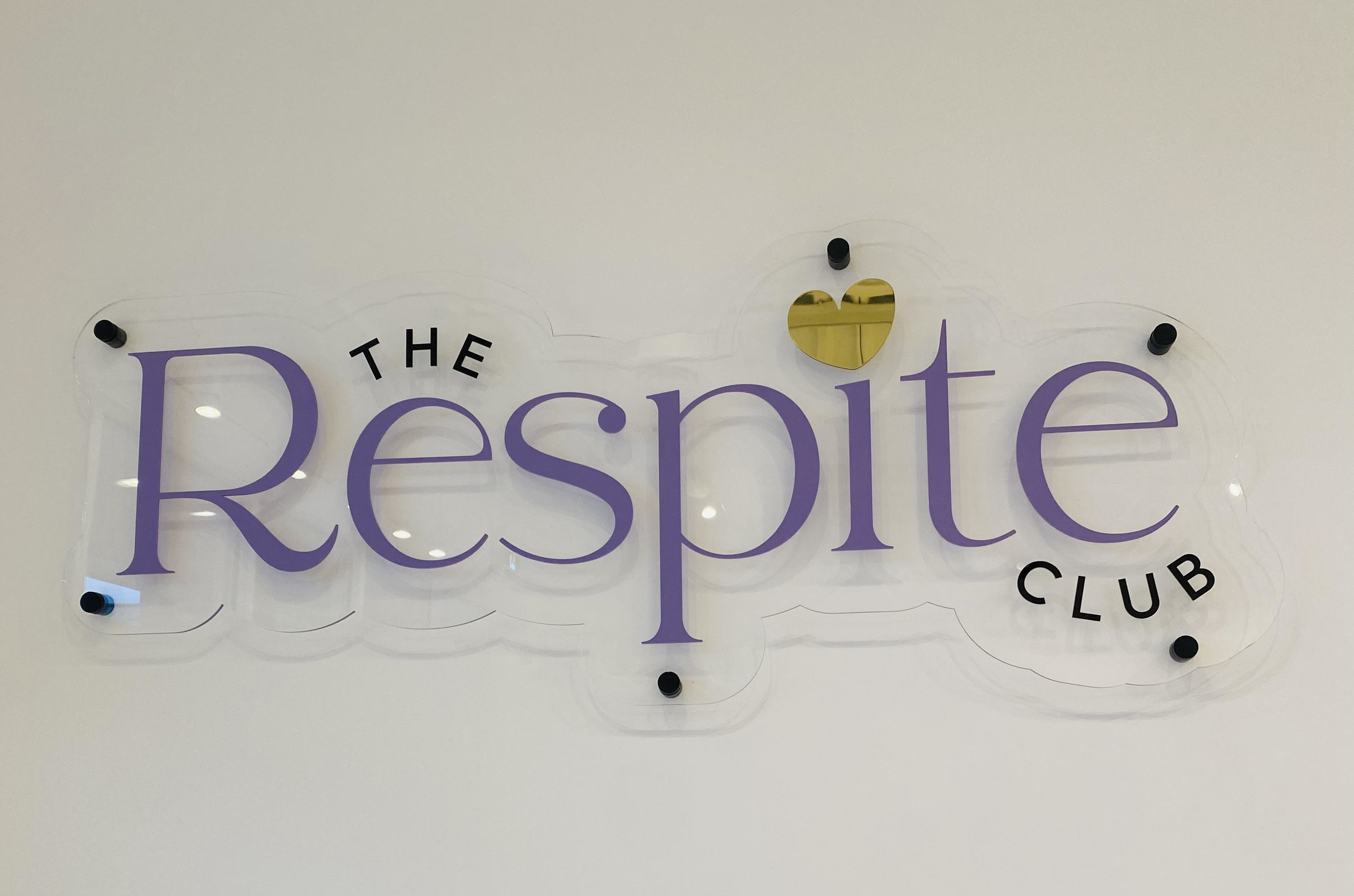 Pancarte « The Respite Club » avec un cœur stylisé sur un écran clair et rétroéclairé