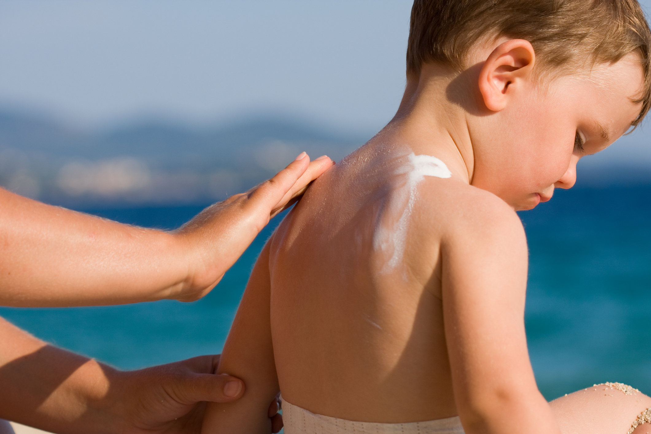 Woman applying sunscreen on a child&#x27;s back
