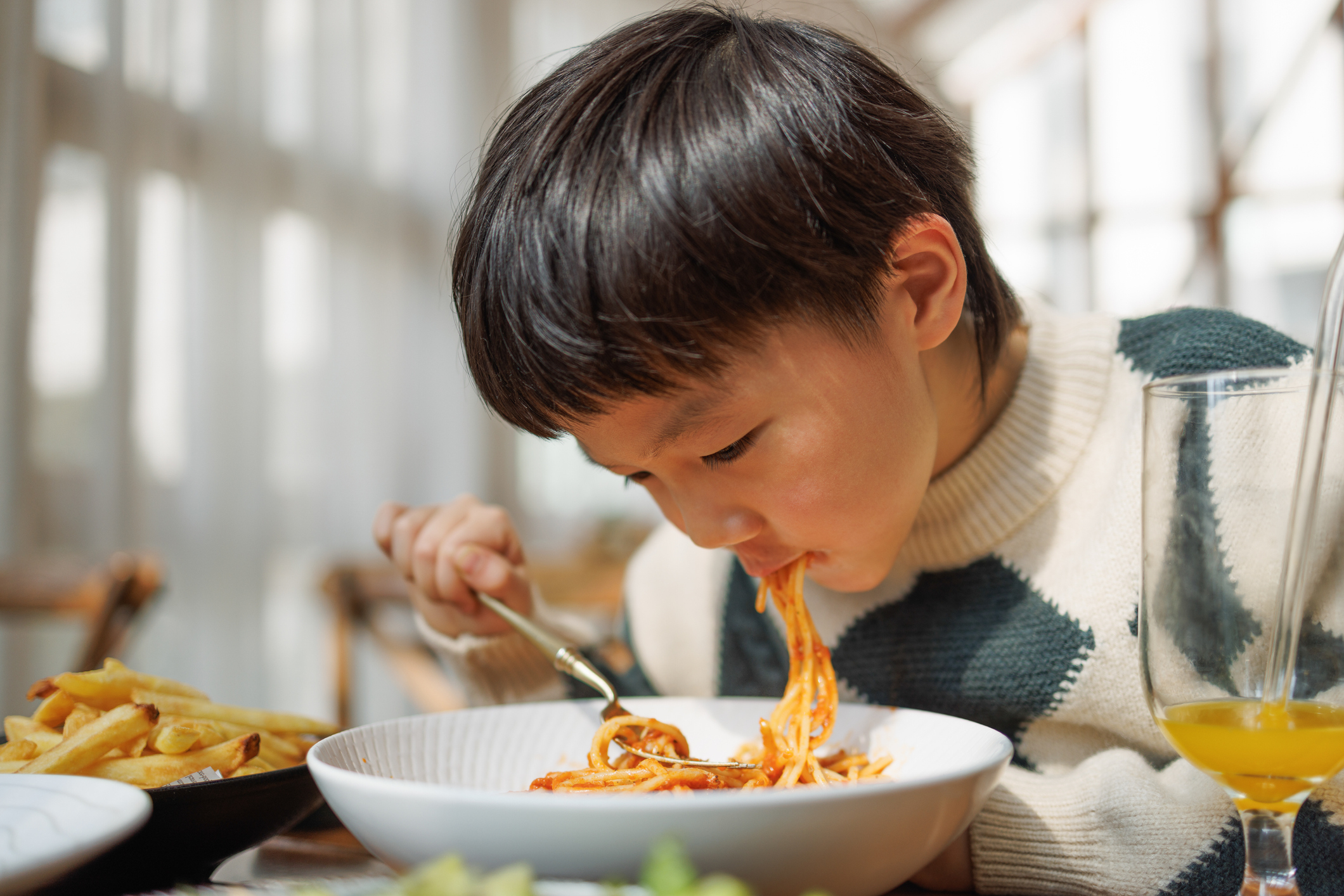 A young boy eating spaghetti