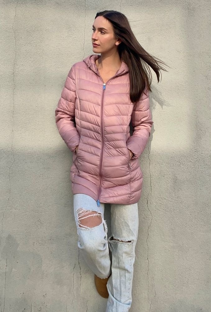 a person wearing a dusty rose colored slim-fitting puffer coat