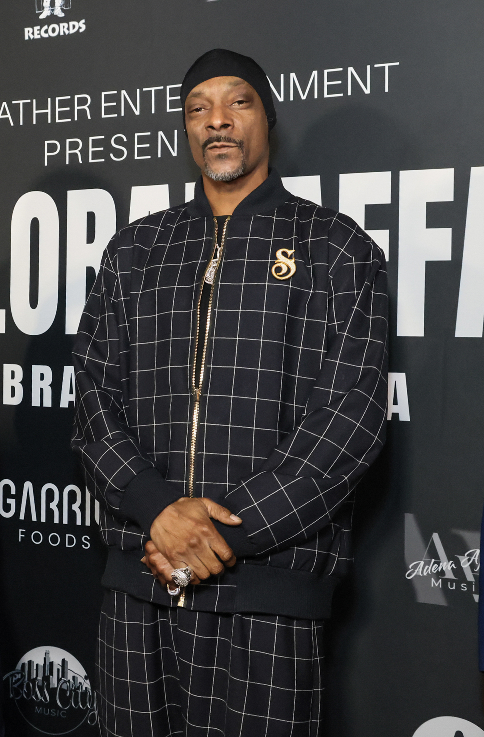 closeup of him in a plaid jacket and pants with a durag and greying goatee