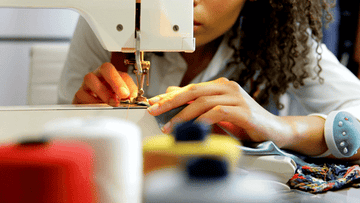 Person sewing fabric on a sewing machine, focus on hands and machine