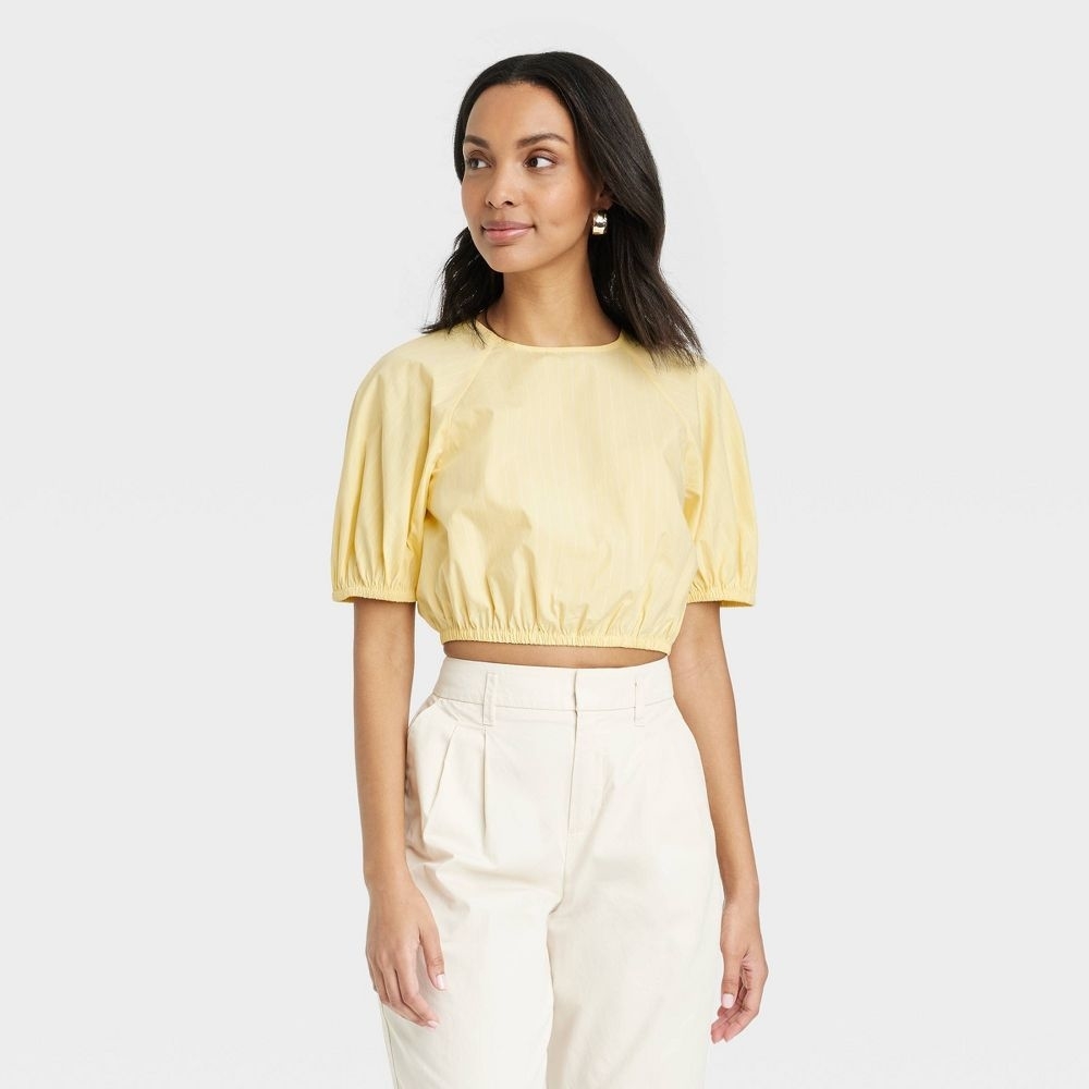 a person in a yellow short sleeve puff shoulder crop top
