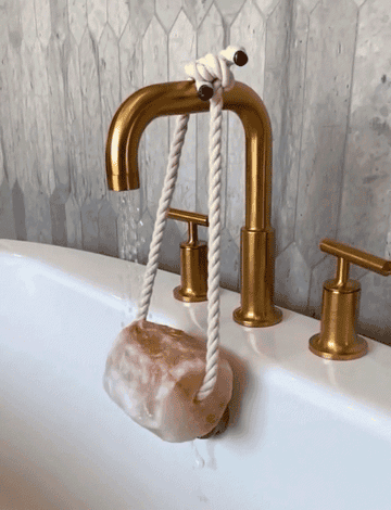 Gold faucet with rope-tied salt stone dangling from it
