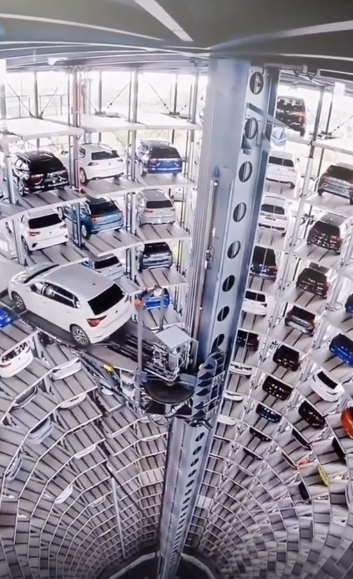 Parked cars in an enormous circular parking lot in the shape of a tower