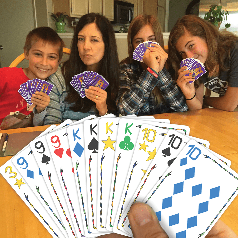 People playing the game holding multicolor numeric and face cards.
