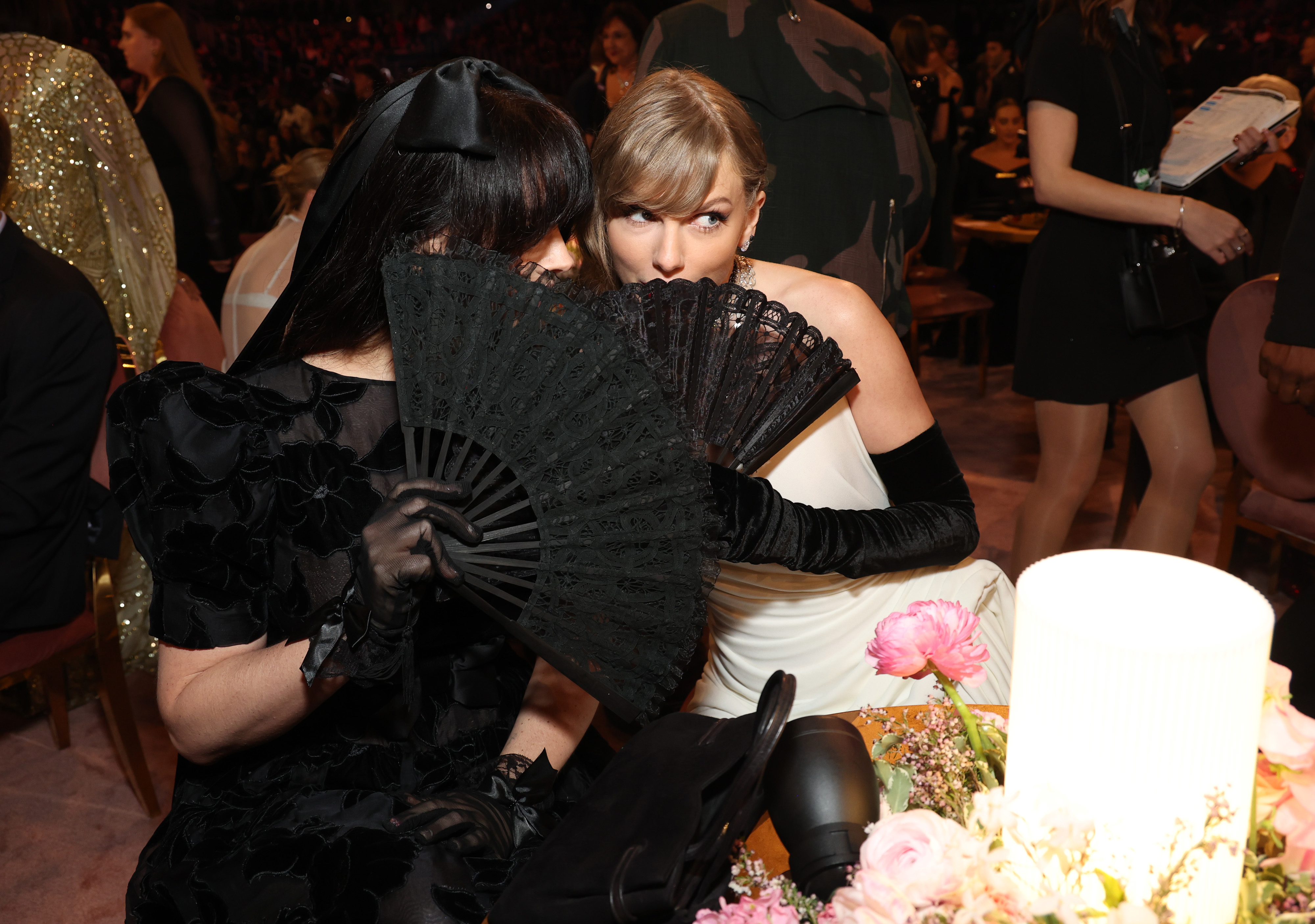 Close-up of Taylor and Lana sitting together behind an open fan