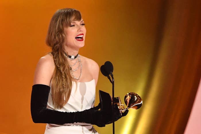 Close-up of Taylor onstage holding a Grammy and wearing opera gloves and a strapless outfit