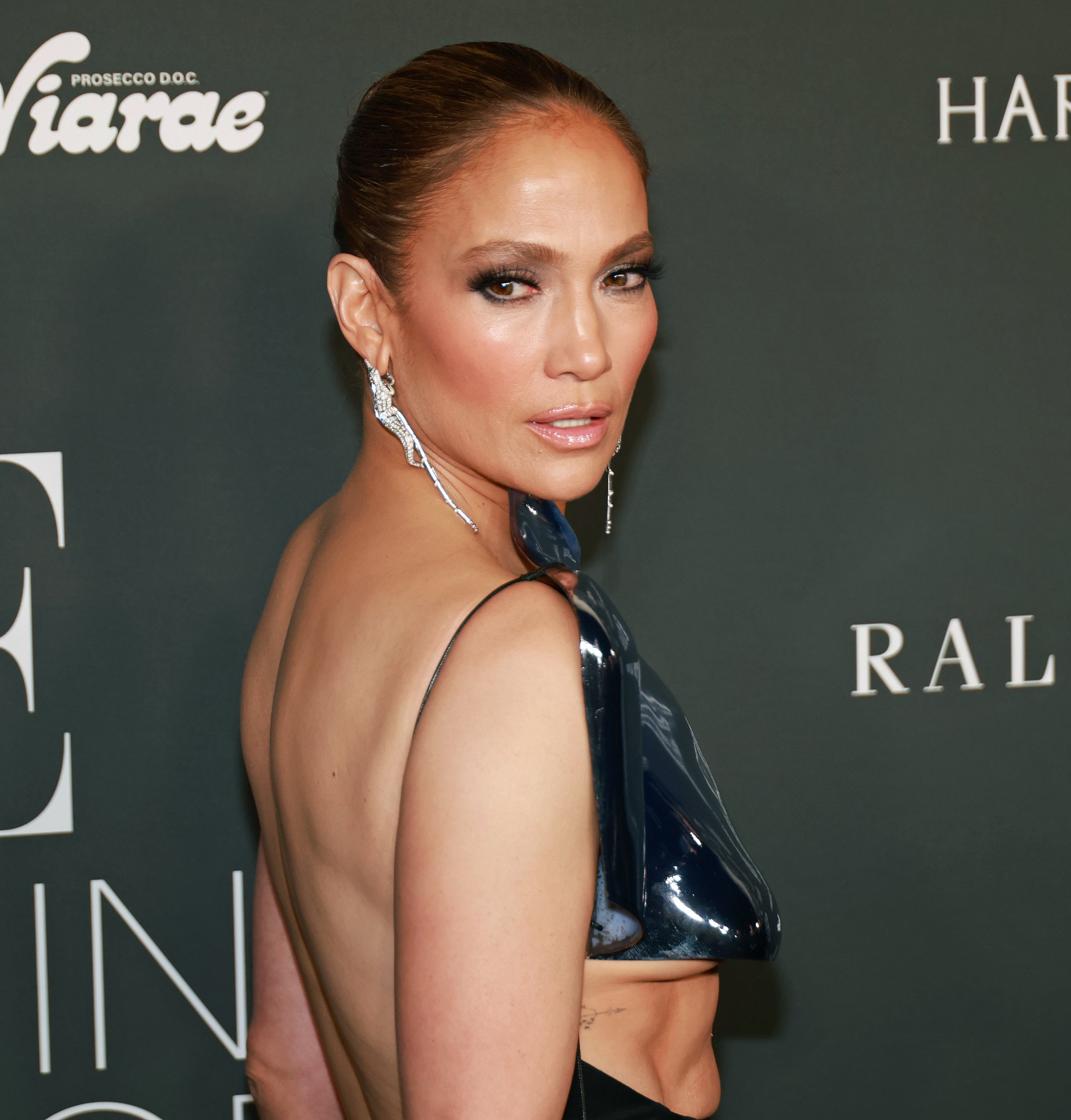 Close-up of JLo at a media event in a backless outfit