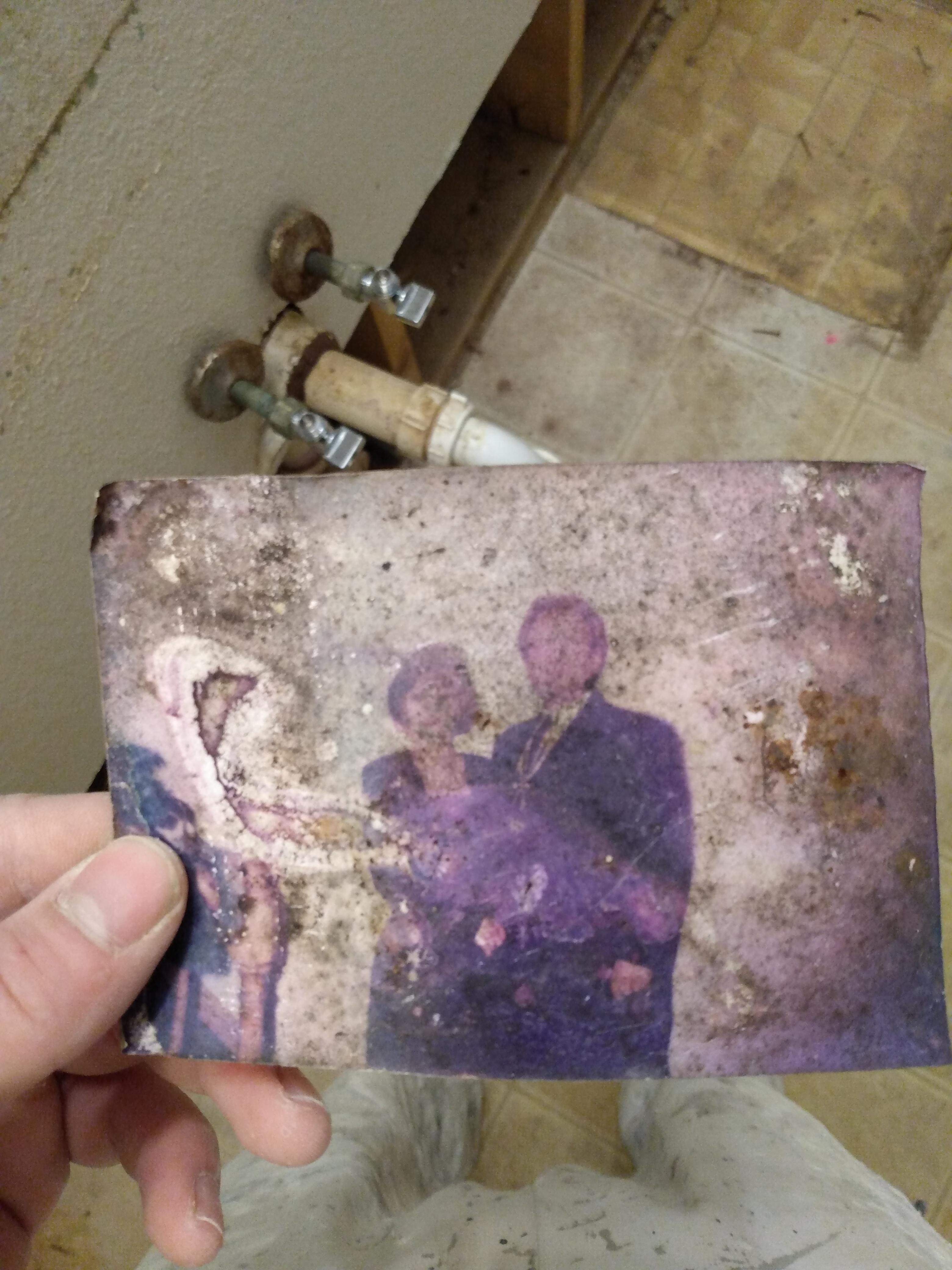 someone holding a damaged old photo of what looks like a couple