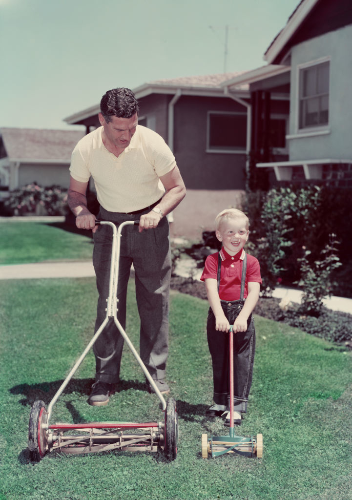 Old-school photo of a dad with his son and they both have lawn mowers