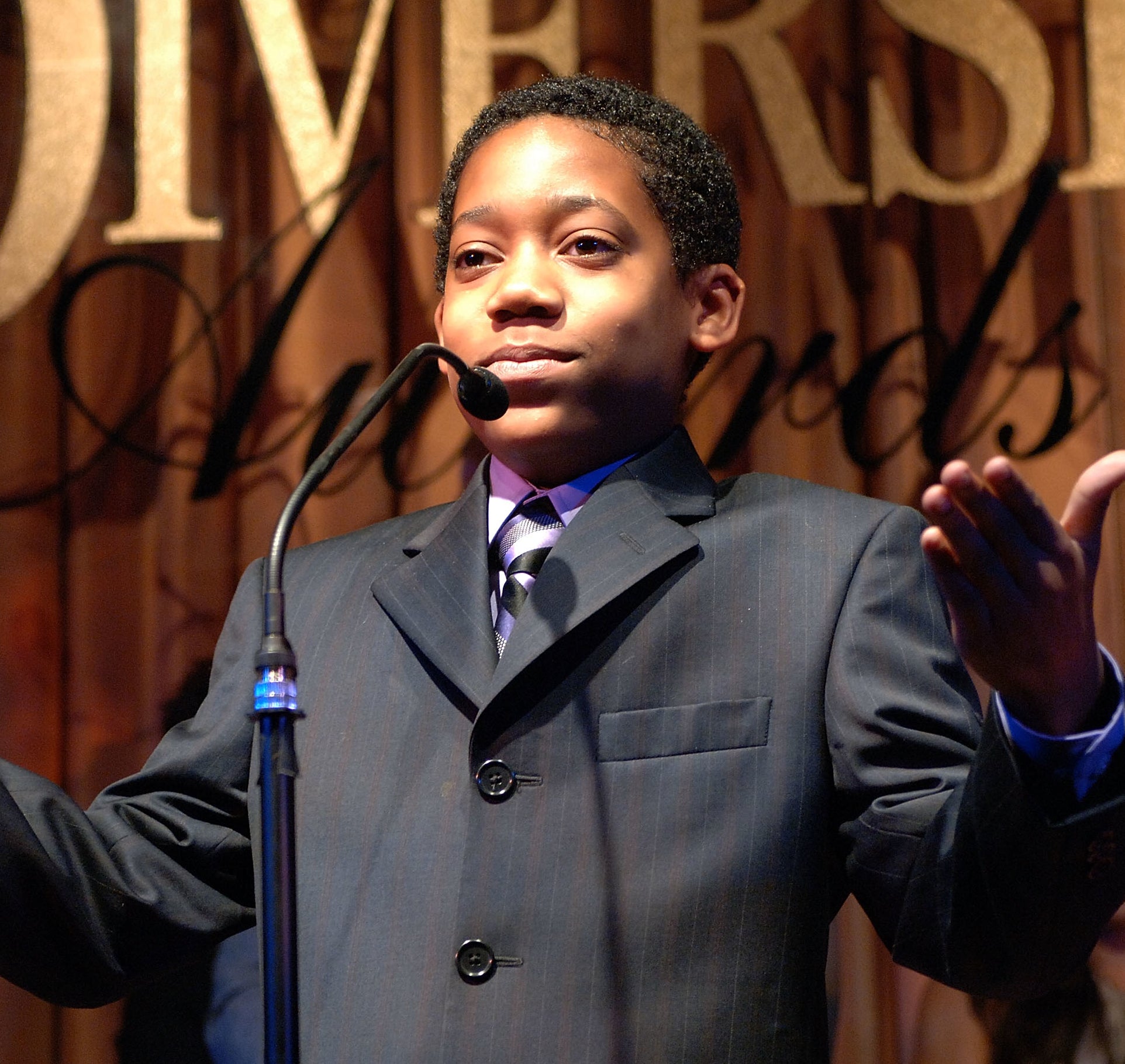 a young tyler in a suit standing at a mic