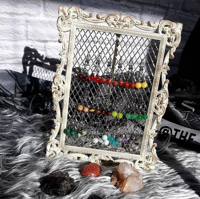 a reviewer photo of the off-white earring holder with multicolored earrings on it