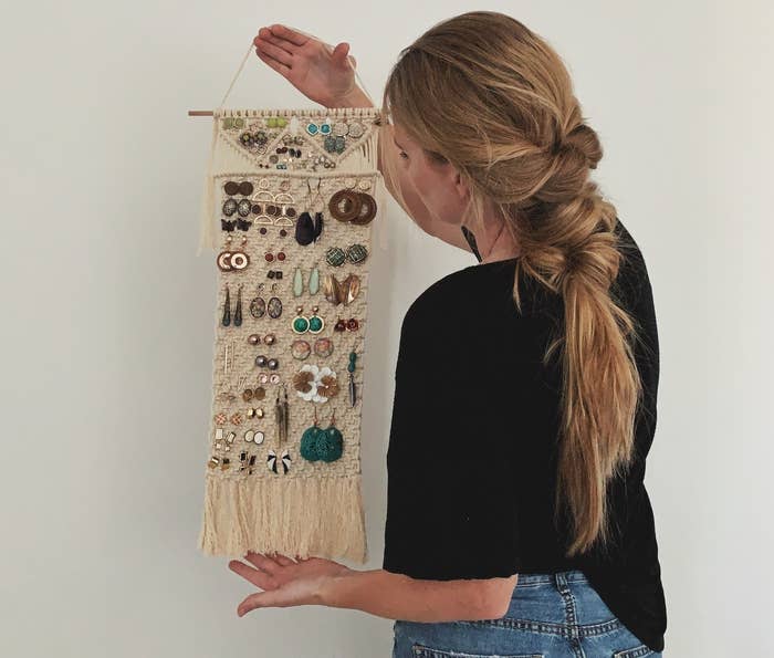a person holding the macrame holder with earrings on it