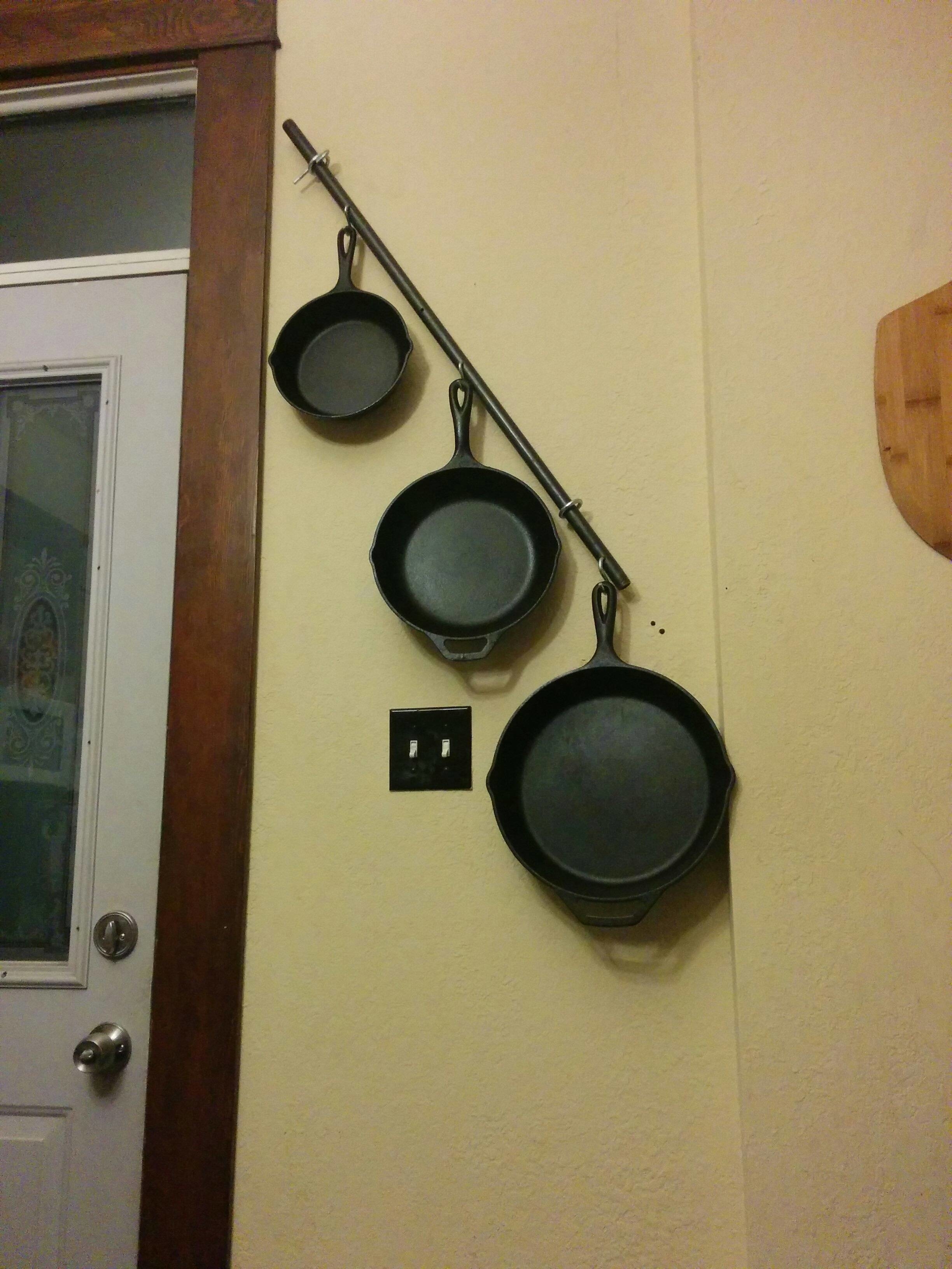 Set of three cast-iron pans hanging on a wall