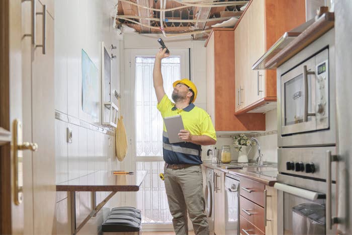 insurance inspector looking inside a gutted ceiling