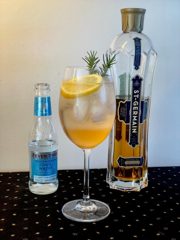 cocktail in a wine glass with a lemon and rosemary garnish