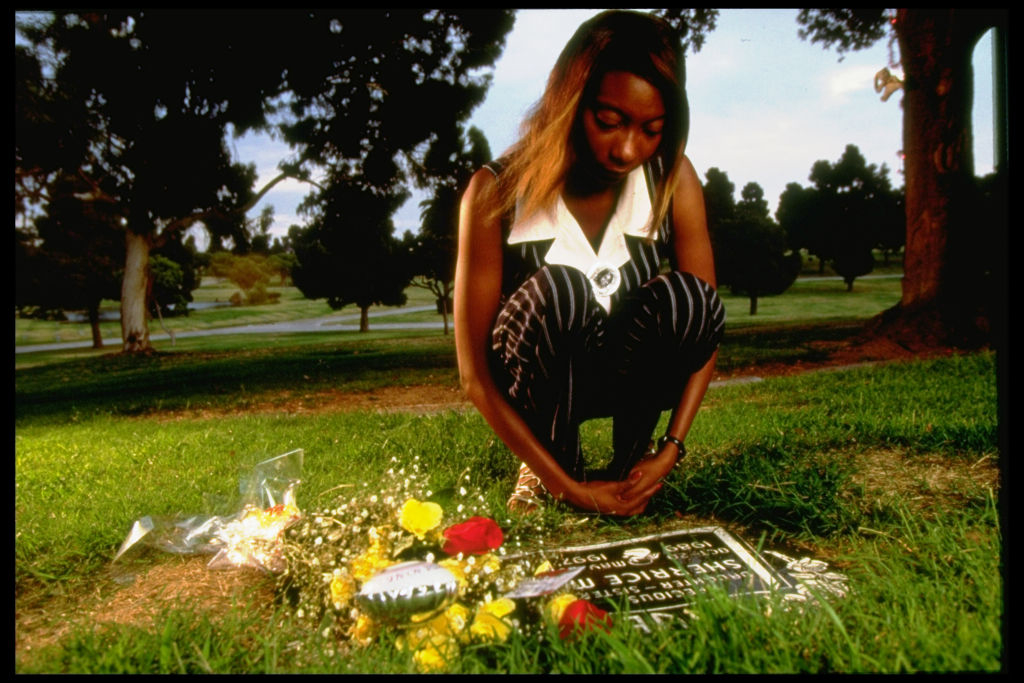 A woman kneeling over a grave