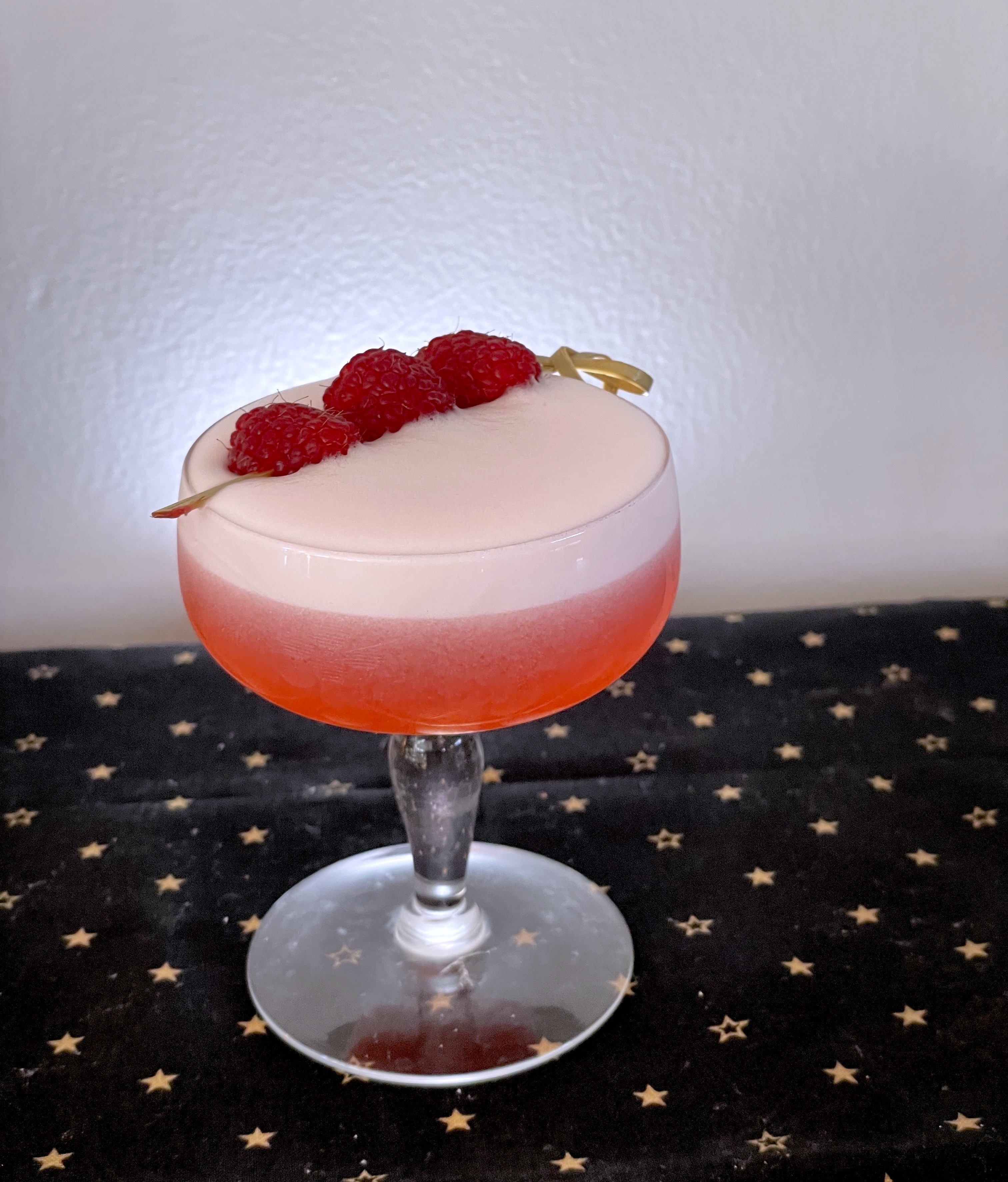 cocktail in a coupe with raspberry garnish