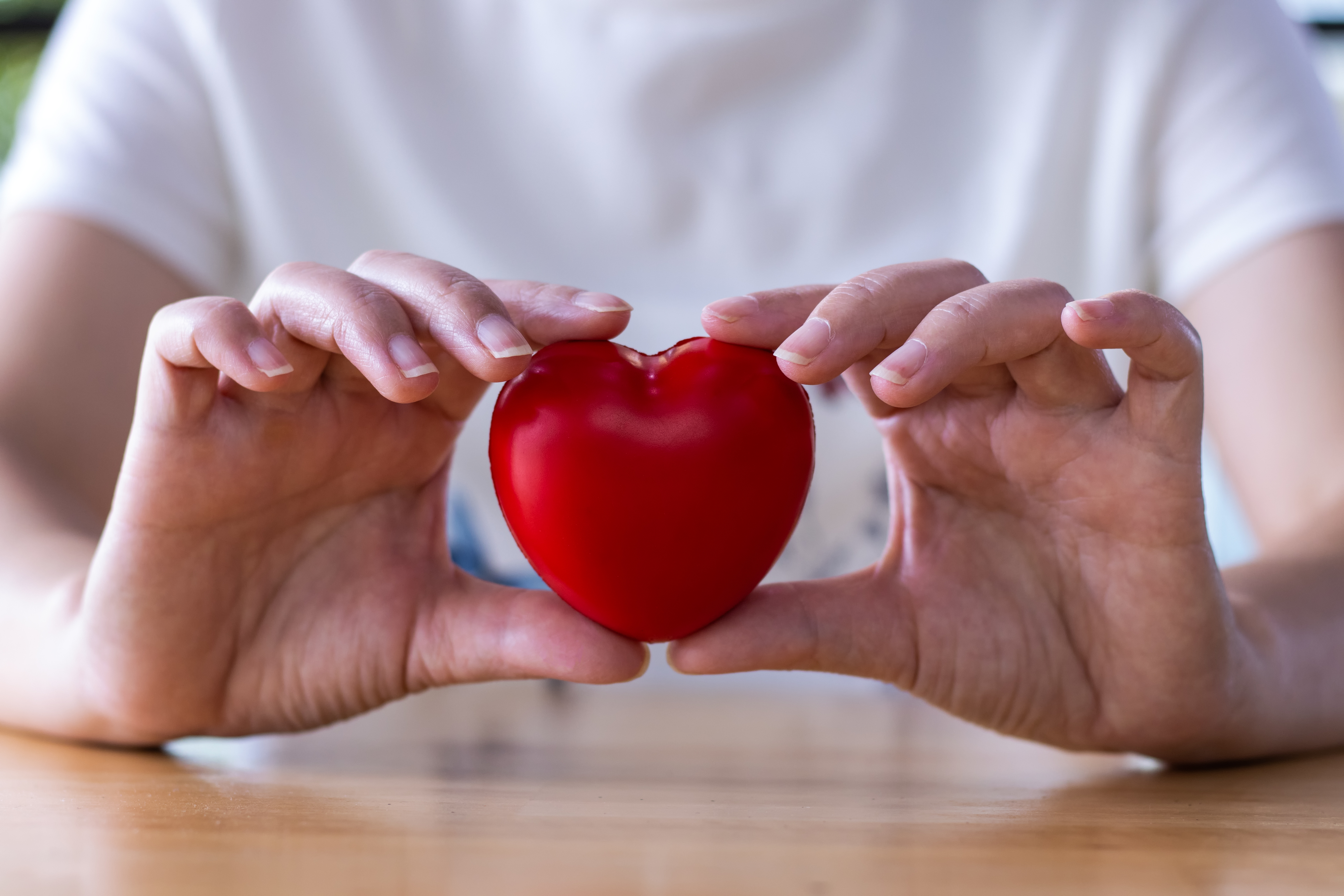 Person holding a heart-shaped object, promoting heart-health awareness