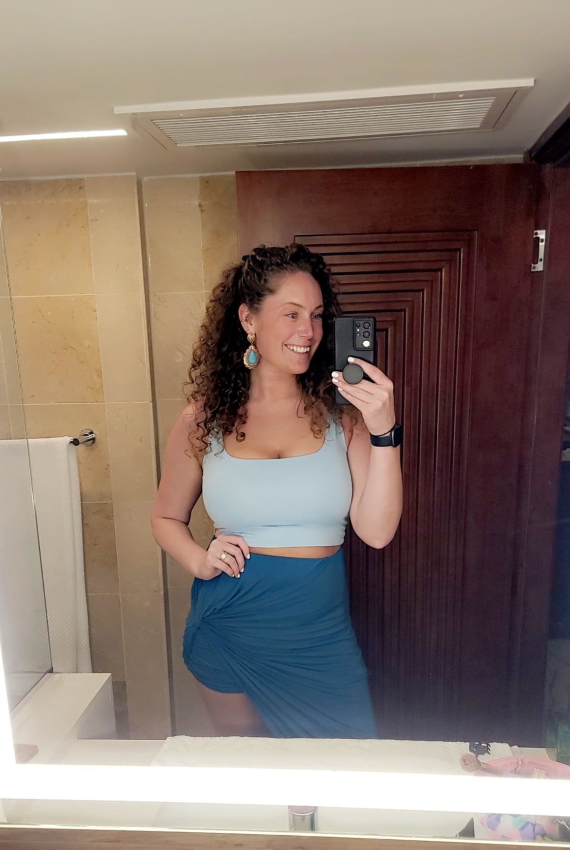 Woman in a blue crop top and skirt ensemble taking a mirror selfie