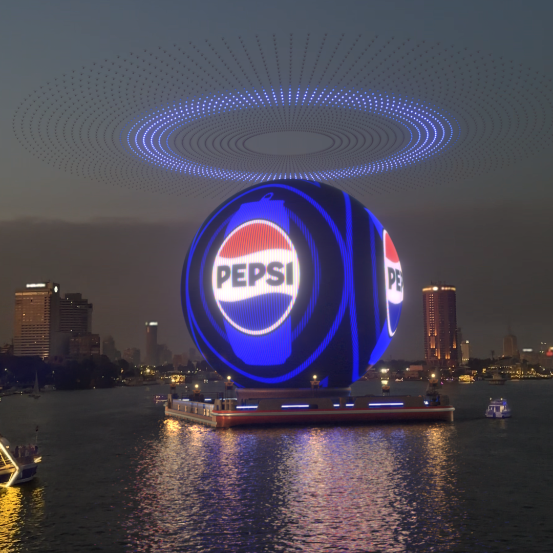 Pepsi logo displayed on a spherical drone light show above a city&#x27;s waterfront at night