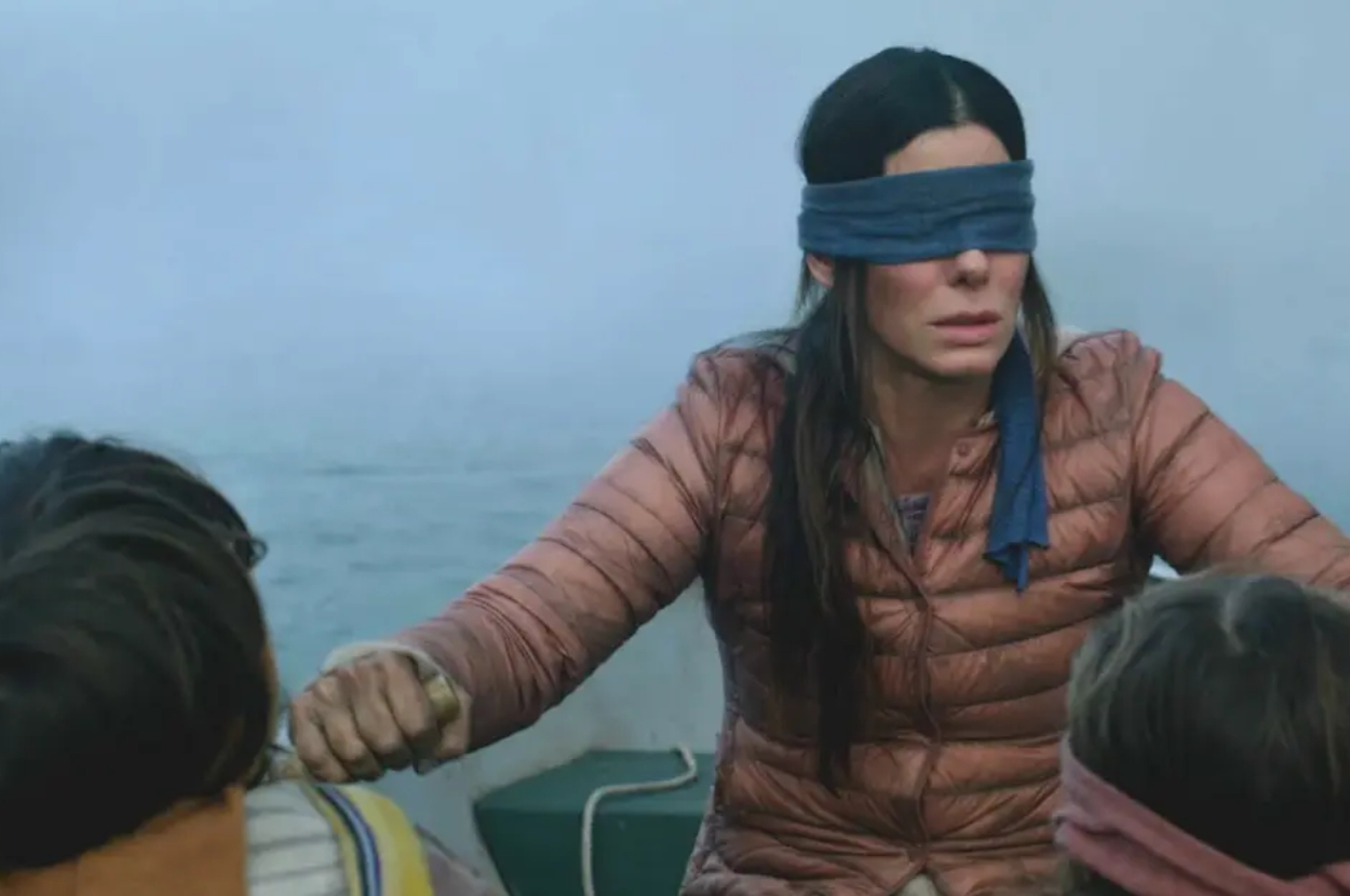 Sandra Bullock blindfolded, leading two children on a boat, in a tense scene from a movie