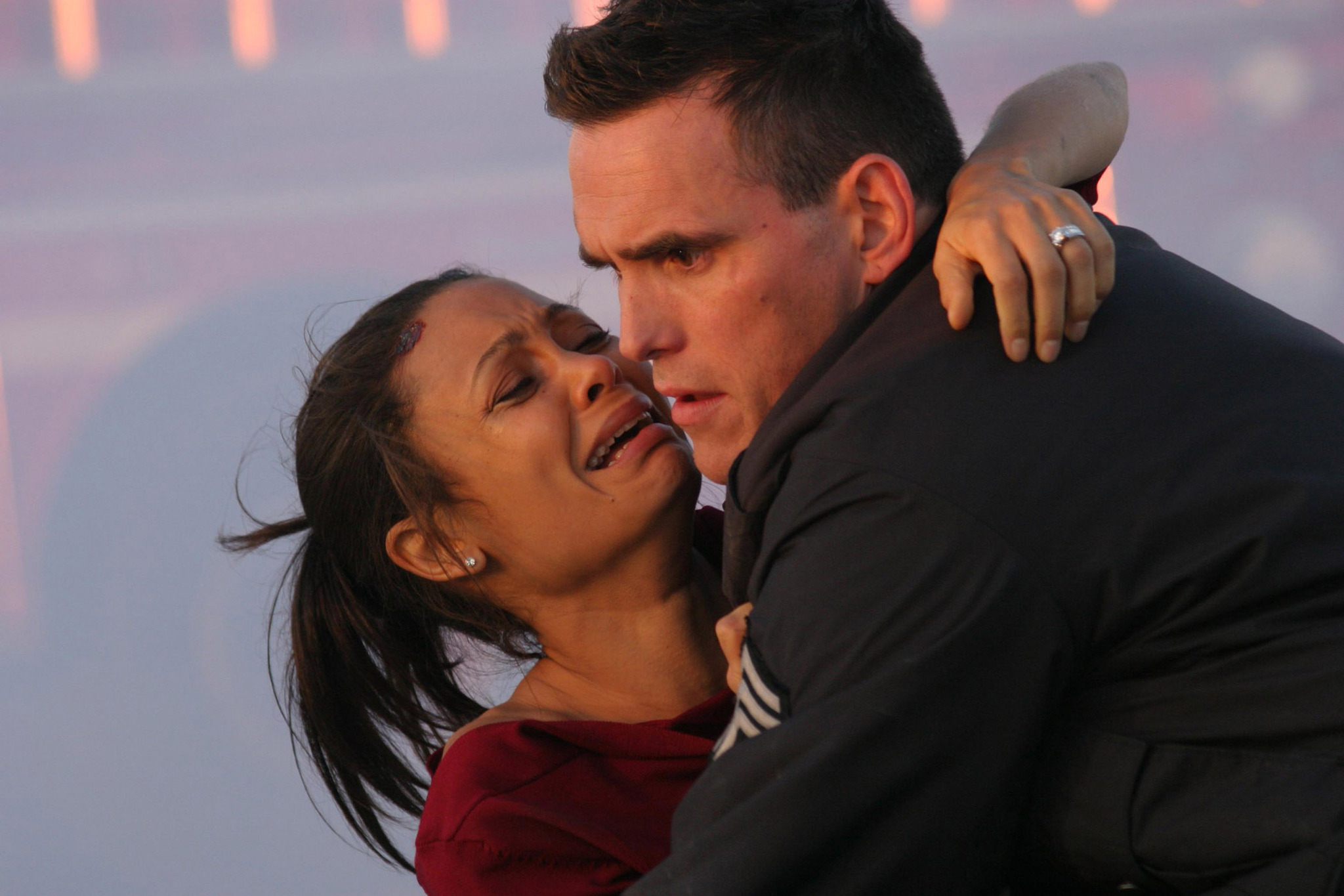 Two actors portraying intense emotion, the woman appears distraught and the man looks concerned, in a close embrace