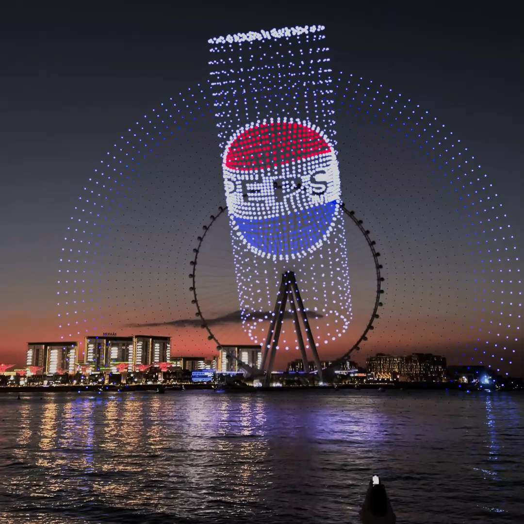 Giant Ferris wheel illuminated with light display of a prescription pill bottle over city skyline at dusk