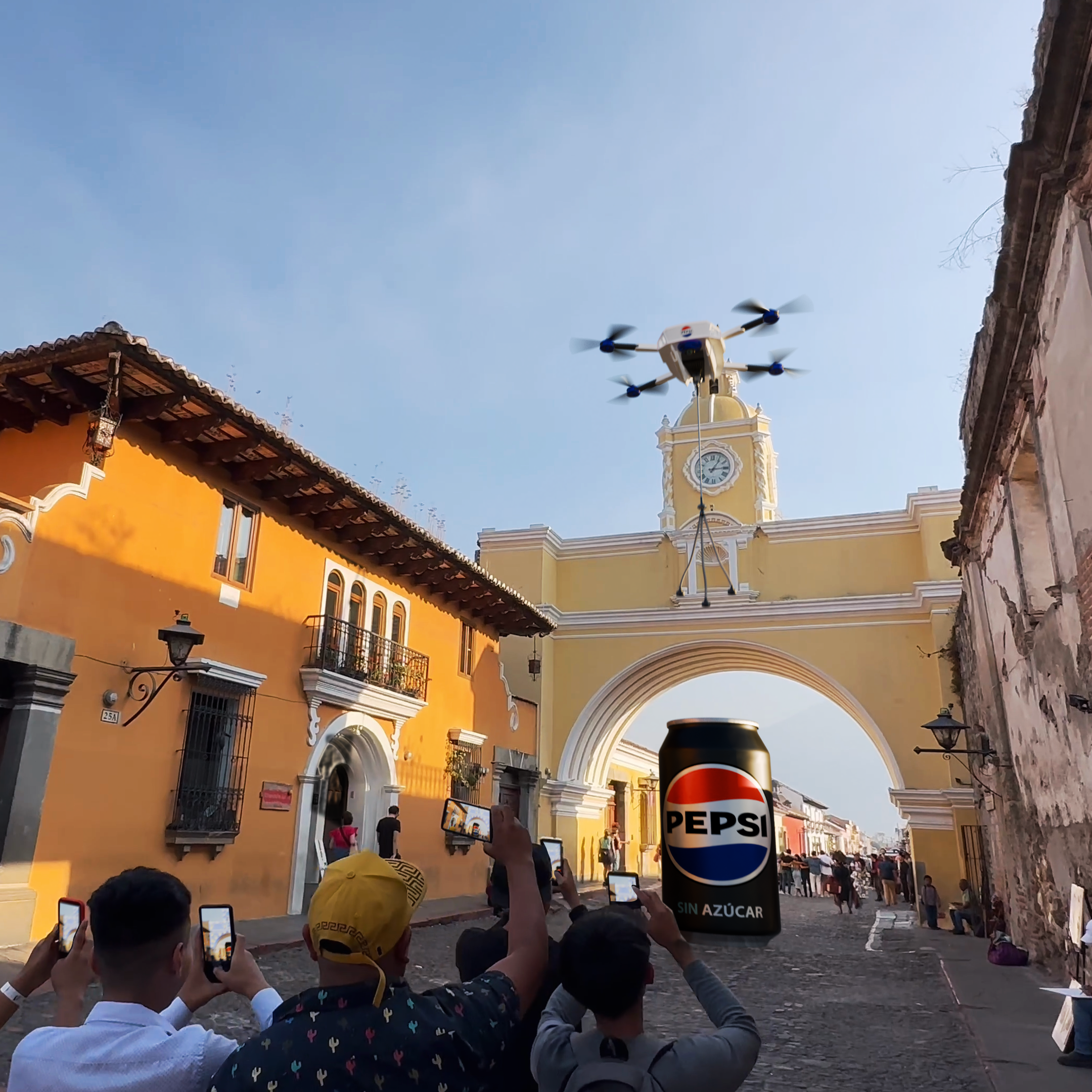 A drone flies over a crowded street by an archway as people take photos. There&#x27;s a large Pepsi can model below the drone