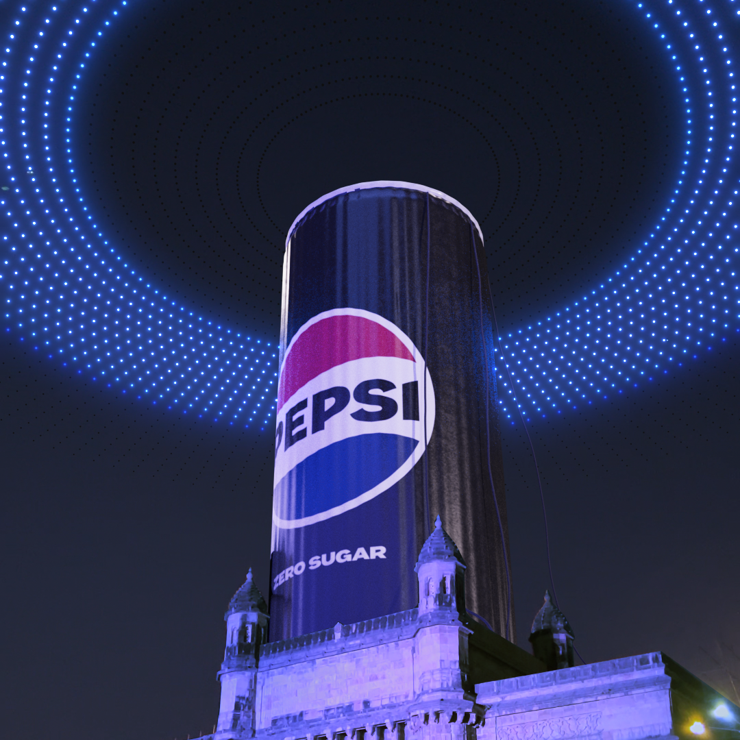 Pepsi logo projected on a cylindrical building at night with a light display above